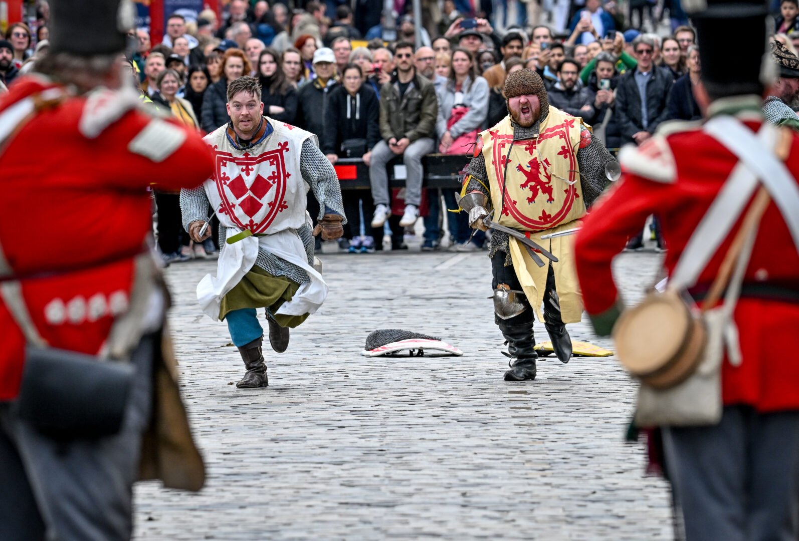 Two Scots soldiers in chain mail running up the Royal Mile to attack the Red Coats