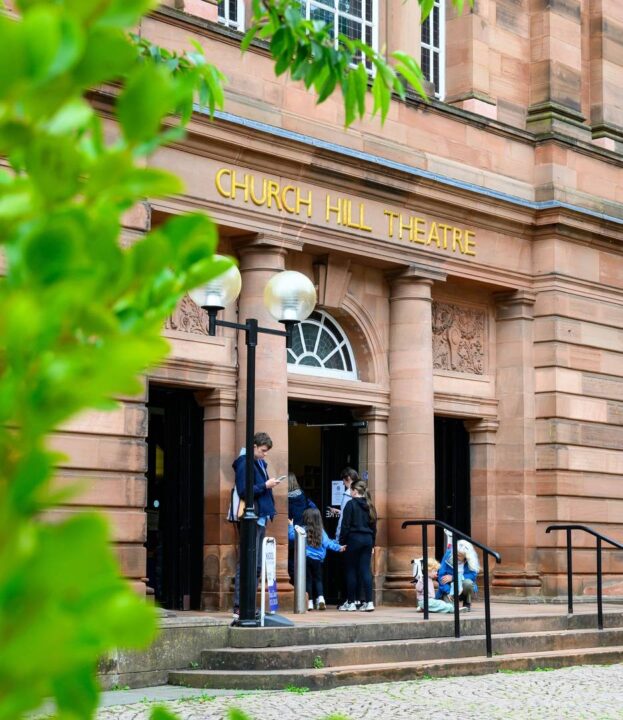 Church Hill Theatre logo poking out from behind a tree branch