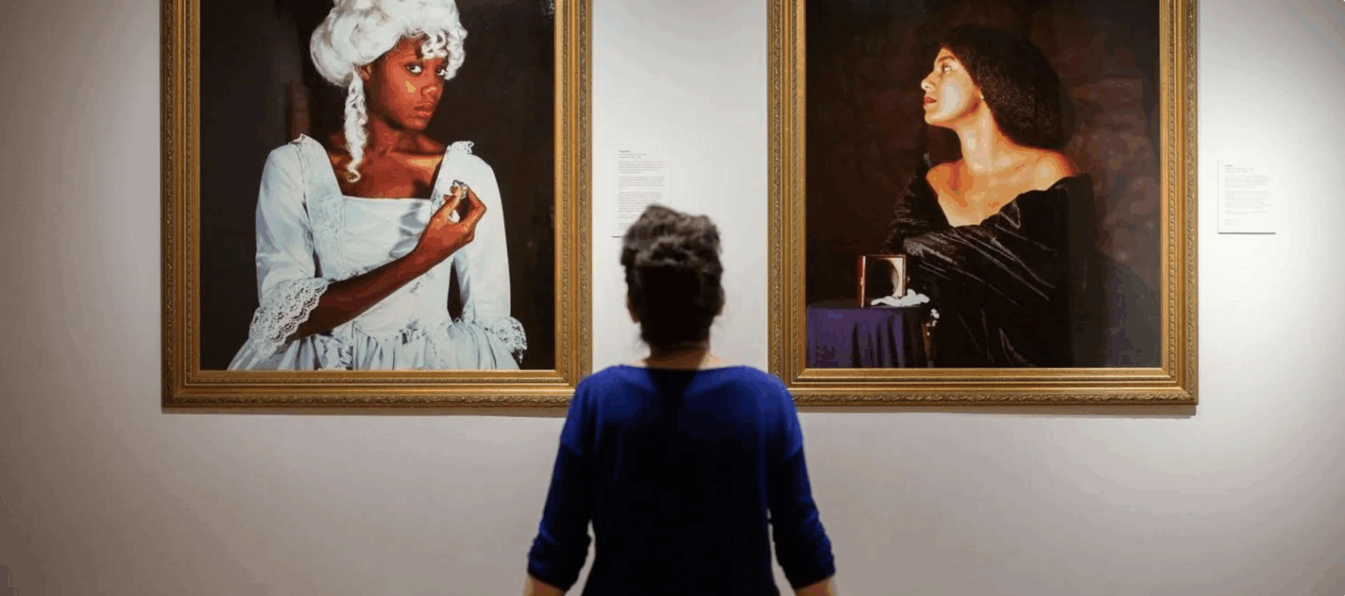 Woman looking at two portraits of two different women