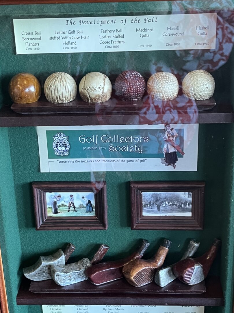 A display case showing historic golf balls and golf club heads