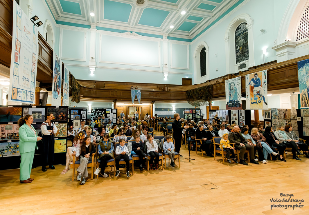 A shot of the crowd attending an event in the church, with artworks from the exhibition around the walls