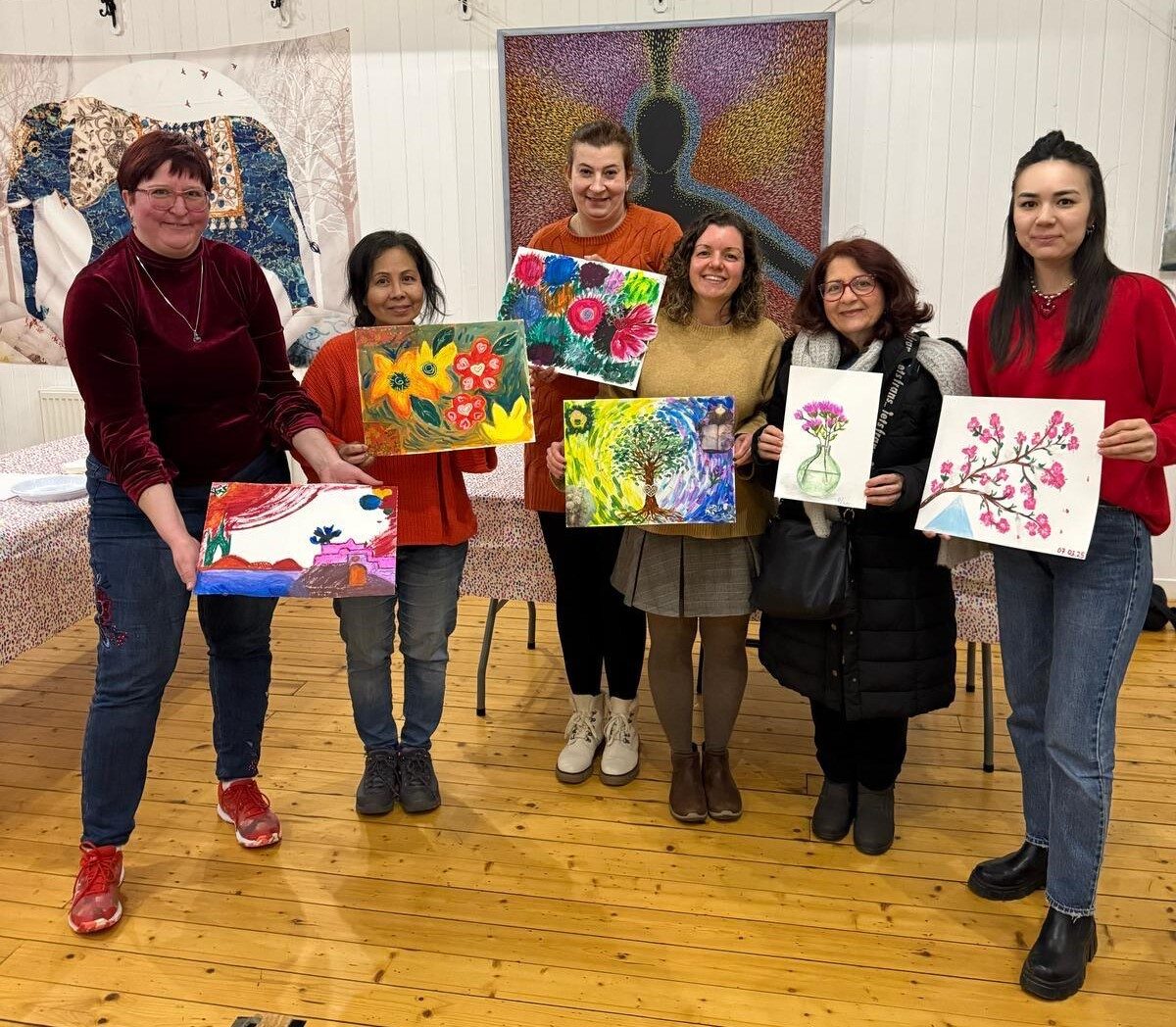 Attendees at an Art and Spirituality workshop show off their artworks - paintings on a horticultural theme