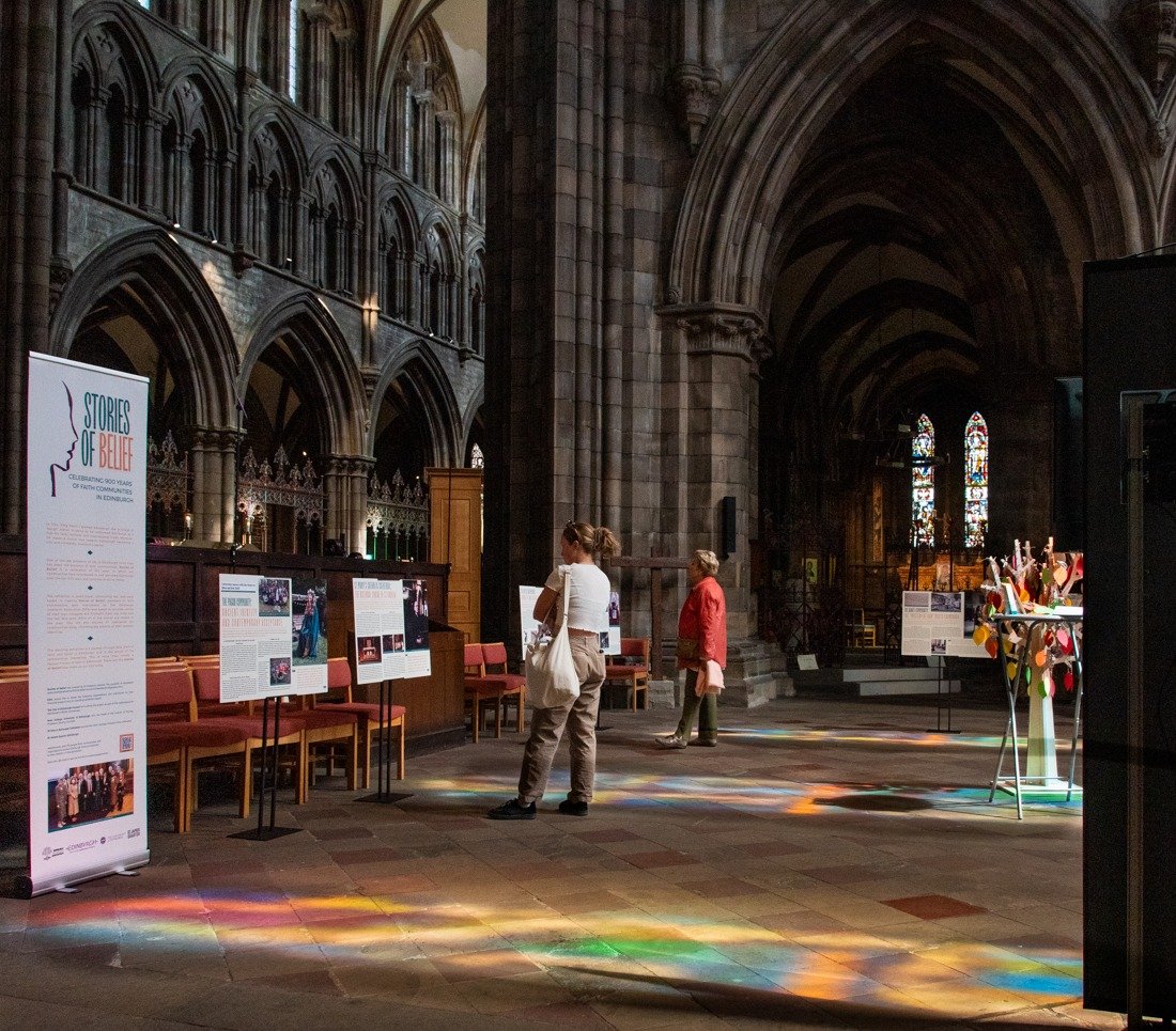 An interior shot of St Mary's Cathedral showing visitors to the Interfaith Exhibition of freestanding panels and a tree with leaves to write on