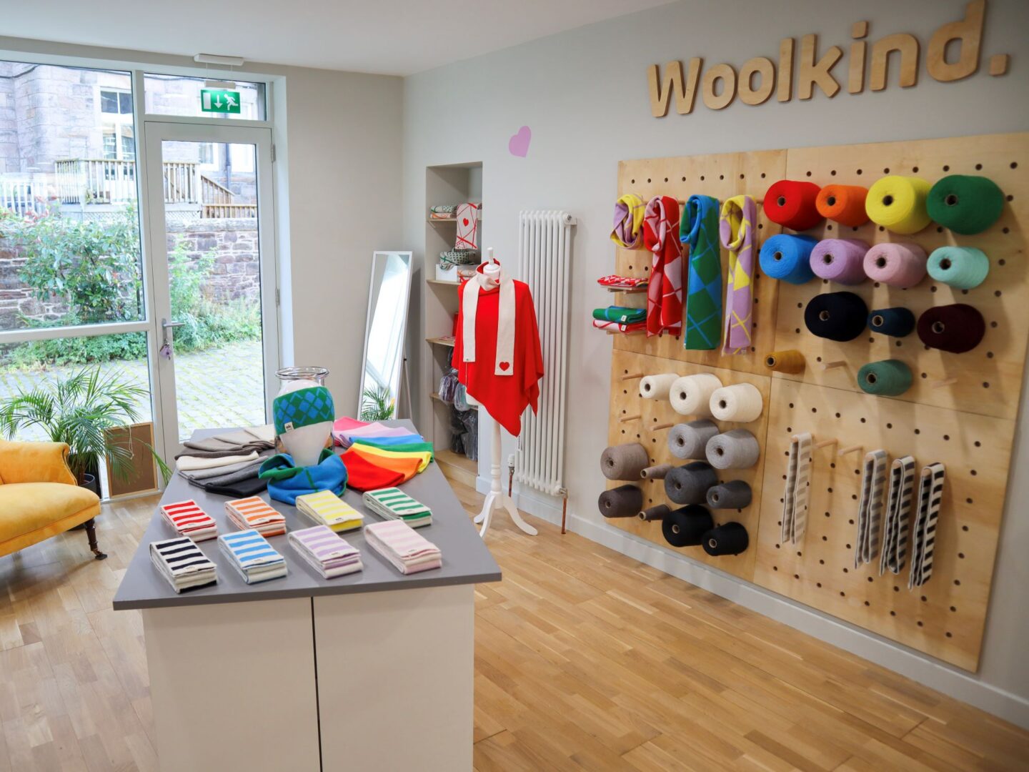 A shop with displays of wool on the wall, on a table and a mannequin.