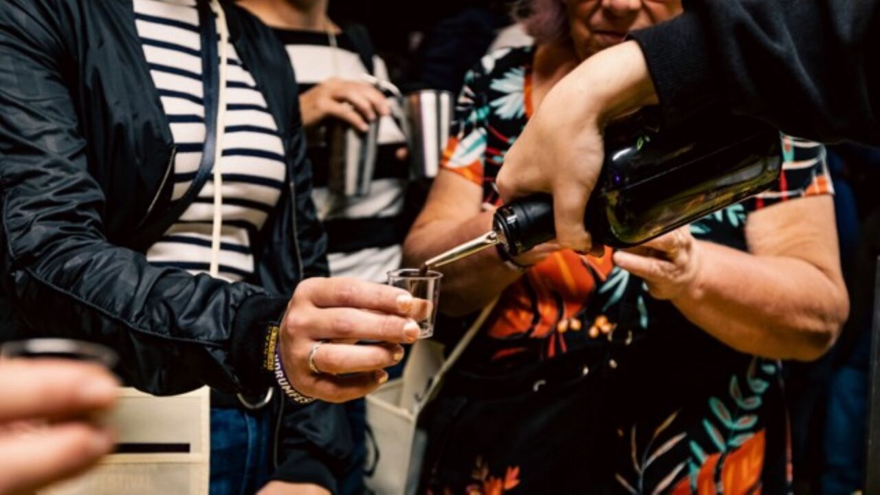 Close-up of a person pouring a drink into a glass.