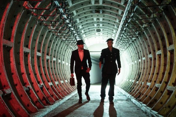 2 men dressed in military and spy outfits walking along tunnel at Edinburgh Nuclear Bunker Tour