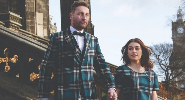 A couple walking in front of Scott's Monument wearing matching blue tartan