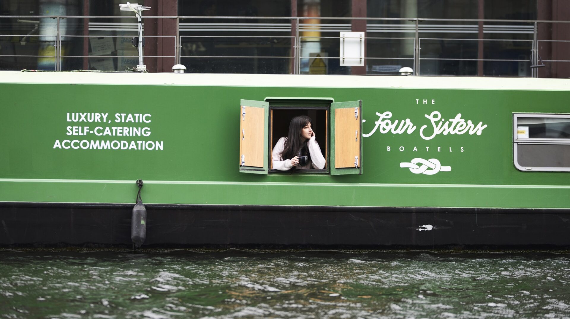 Lady leaning throughthe window of the Sister Boatel Canal boat accommodation.