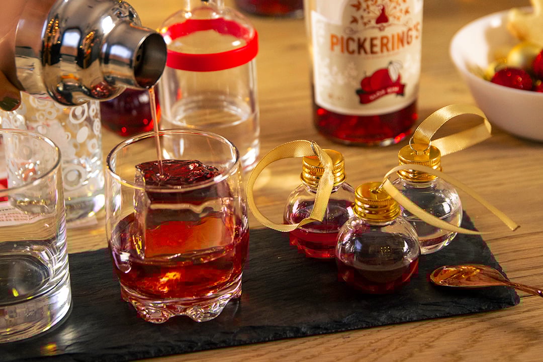 Pickering gin being poured into a glass and to the side there are 3 Pickering Gins baubles.
