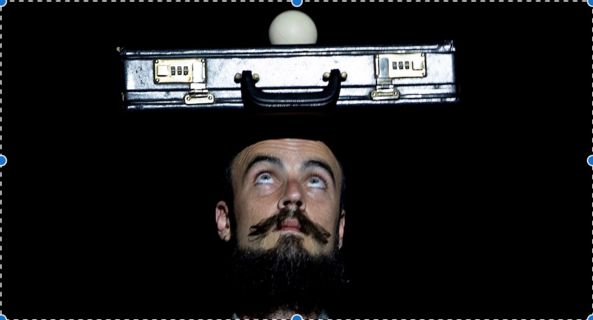 Image of a man balancing a briefcase on his head.