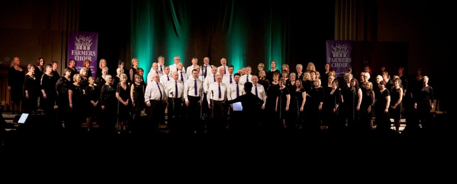 A group of people standing on a stage, and singing.