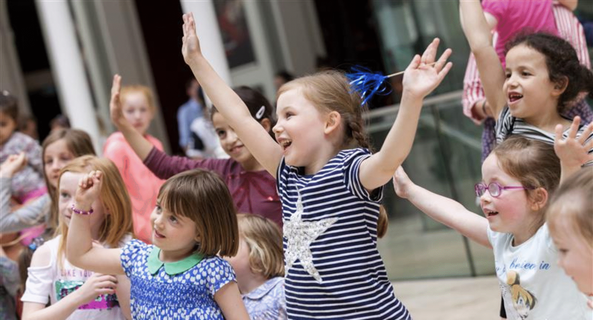 A group of young children dancing and waving their hands in the air.