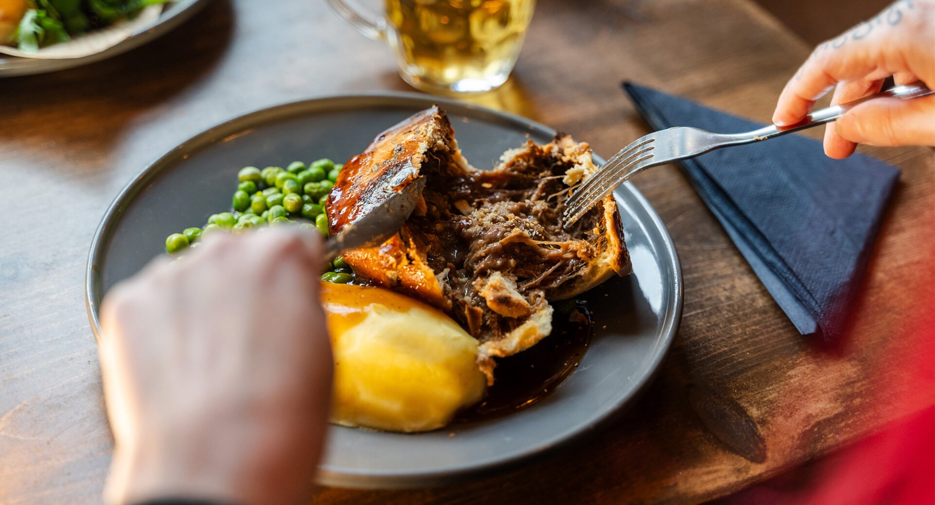 Hands using cutlery to cut into a pie at Johns Coffee House andTavern.