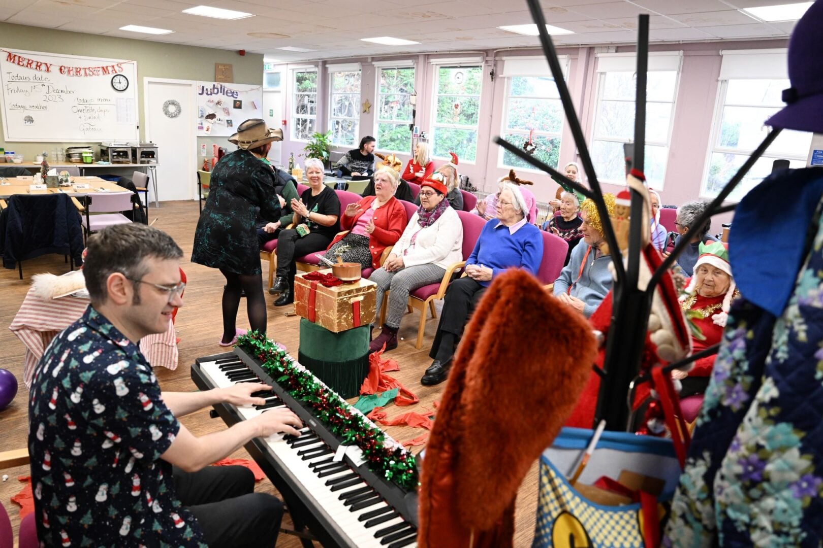 A room full of people, with someone playing the piano.