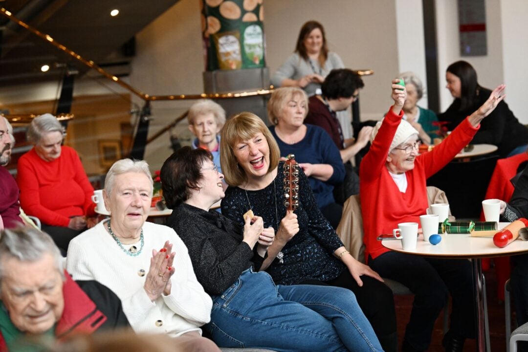 A room full of people singing and playing musical instruments.