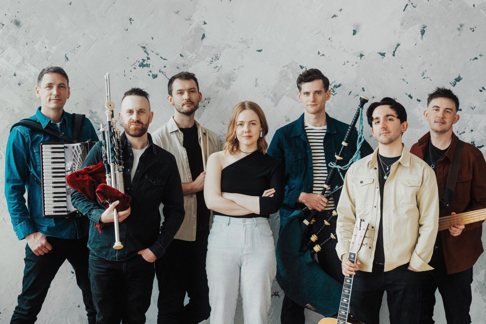 A group of people standing in a row, some of whom are holding musical instruments.