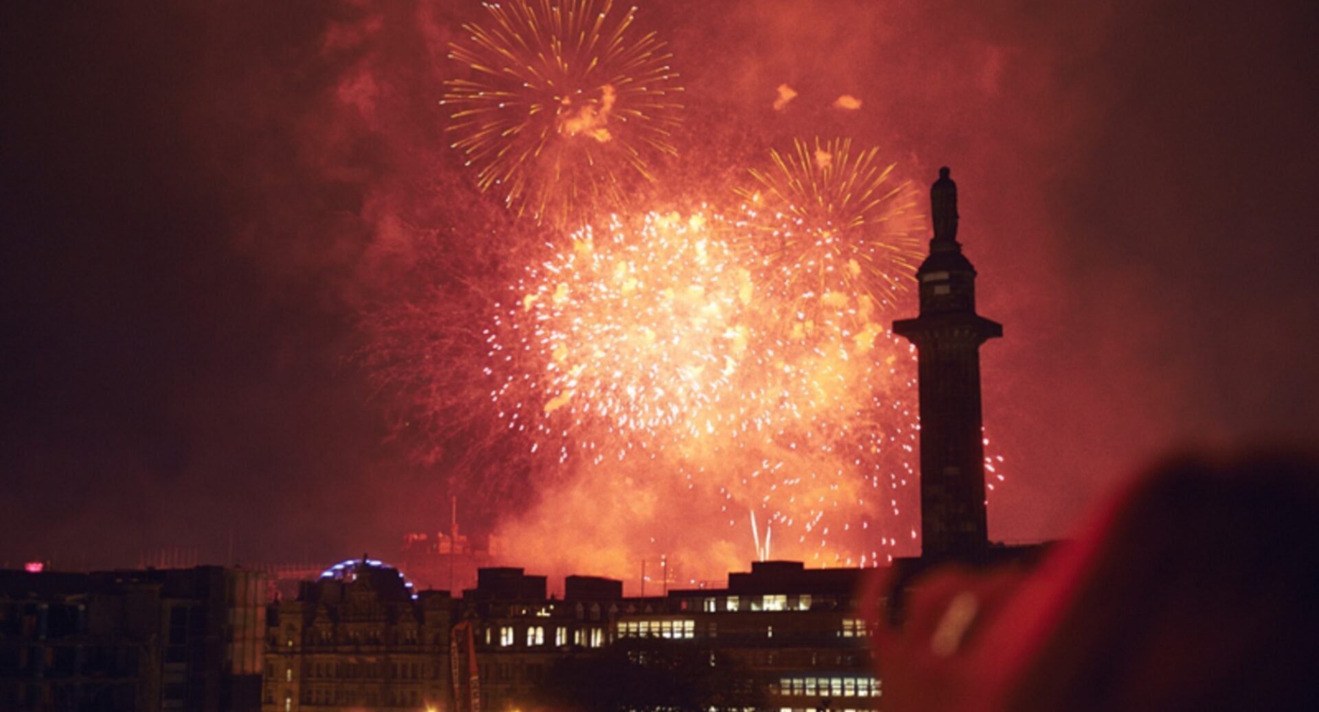 City skyline view at night-time, with bright orange fireworks