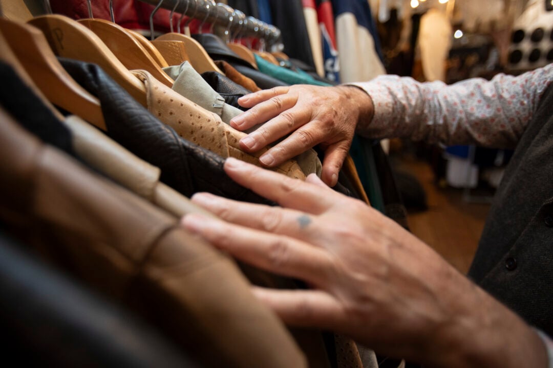 Close-up of a male hand searching a rack in a vintage clothes store