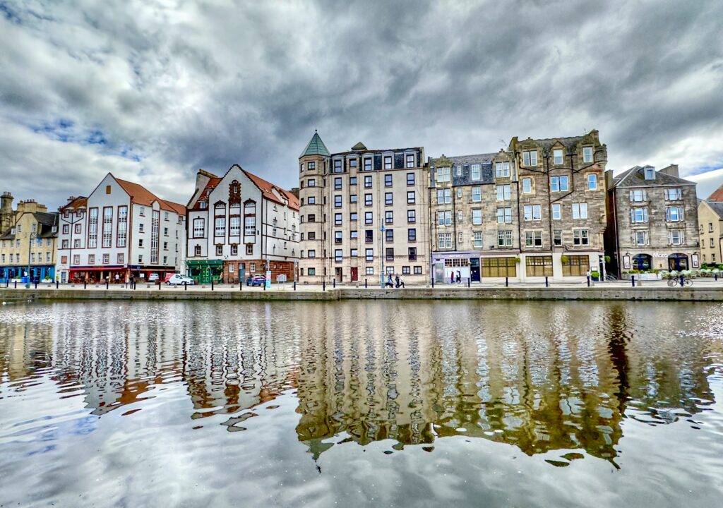 A view of the waterfront buildings in The Shore area of Leith reflected in the Water of Leith under a cloudy sky, Edinburgh, Scotland.
