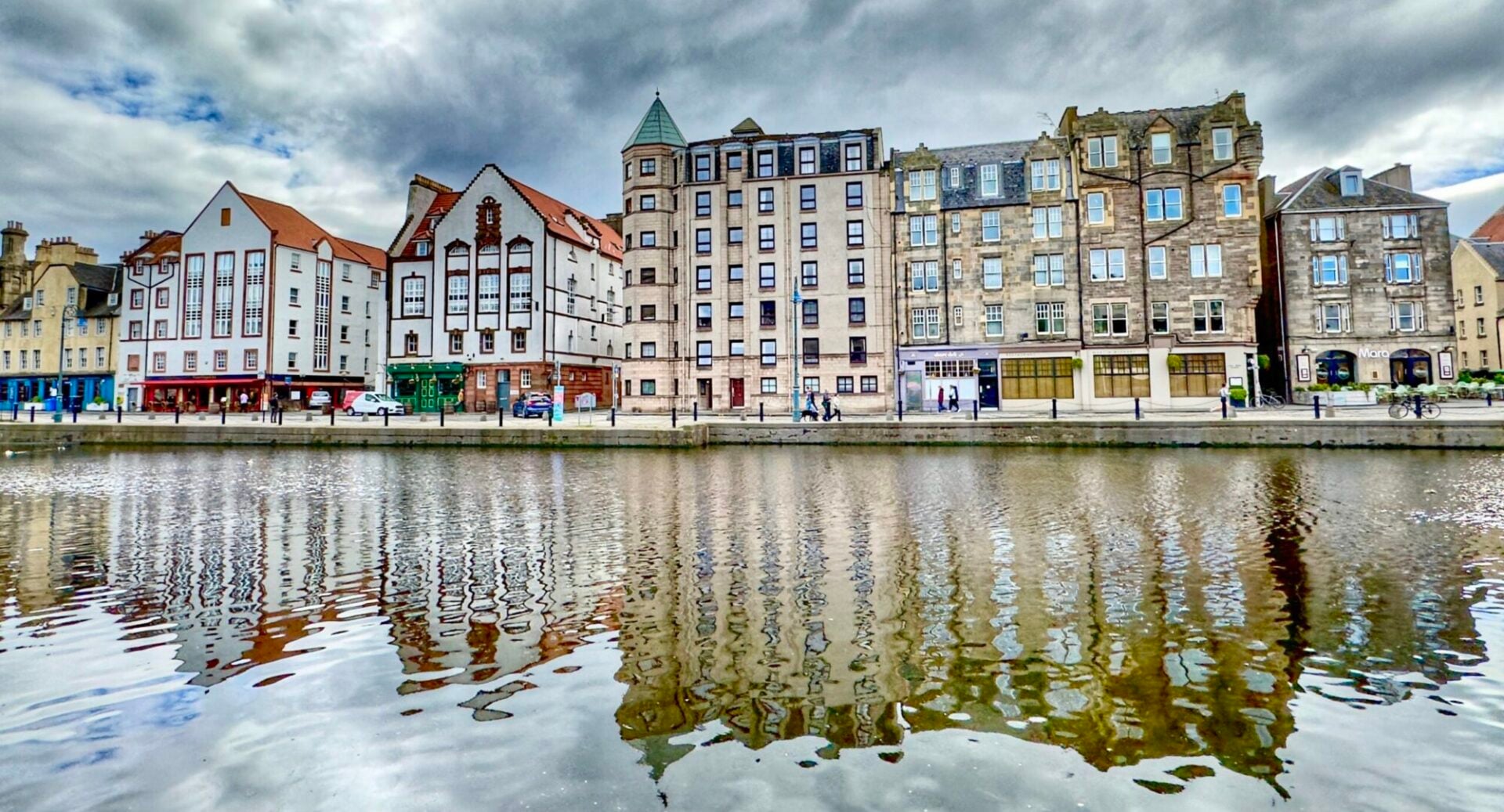 A view of the waterfront buildings in The Shore area of Leith reflected in the Water of Leith under a cloudy sky, Edinburgh, Scotland.