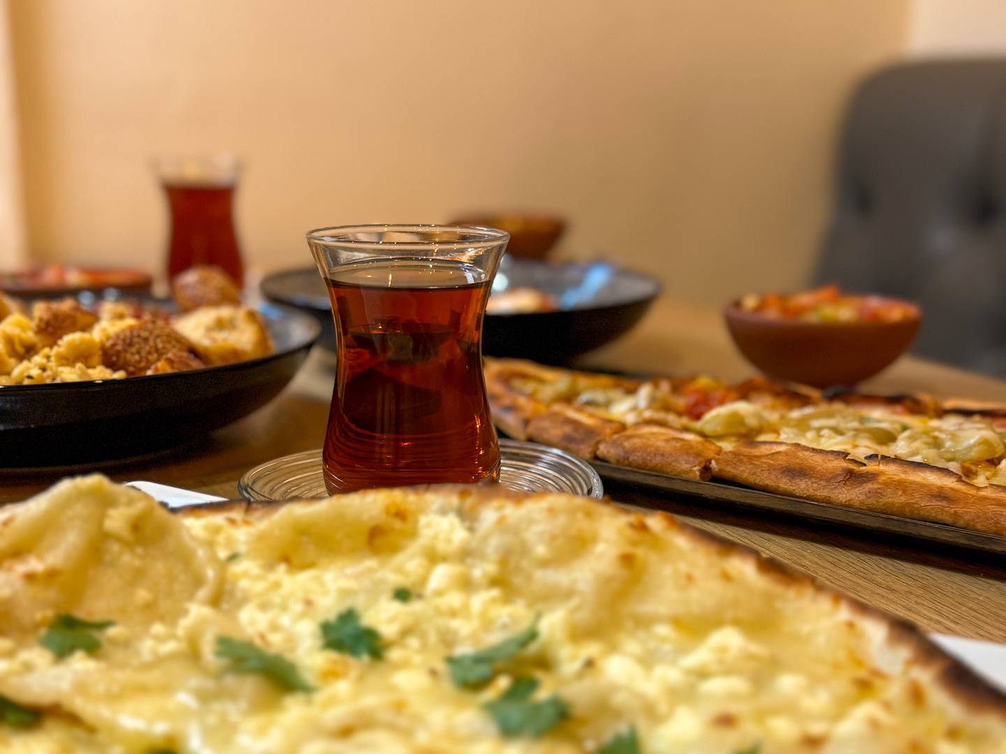 A selection of cheese lahmacun, pide, and eggs with simit, served with Turkish tea.
