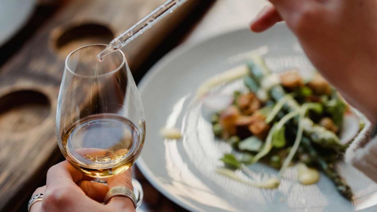 Close-up of a whisky glass and a dish of food.