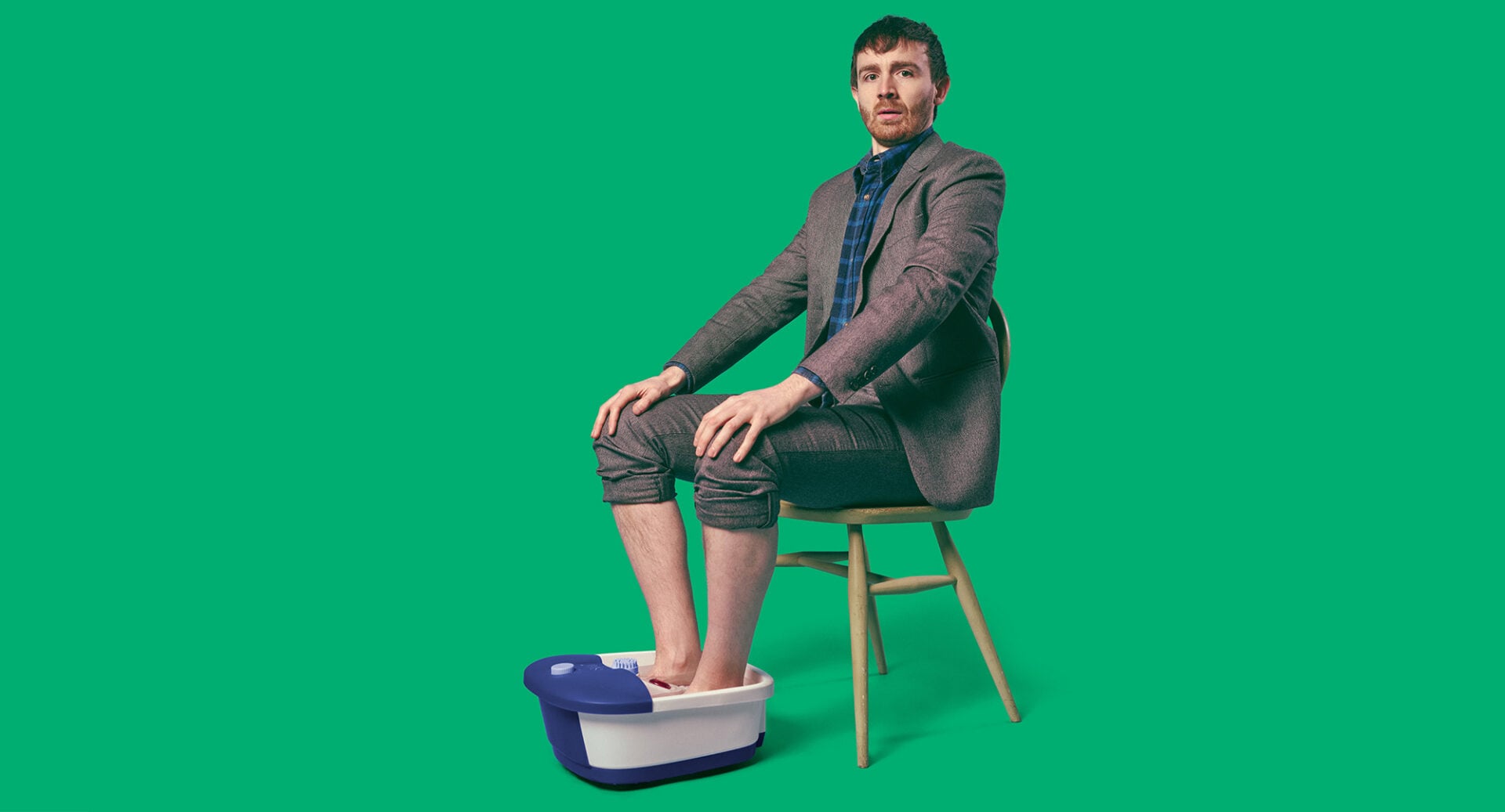 An man sitting with his feet in a foot spa.