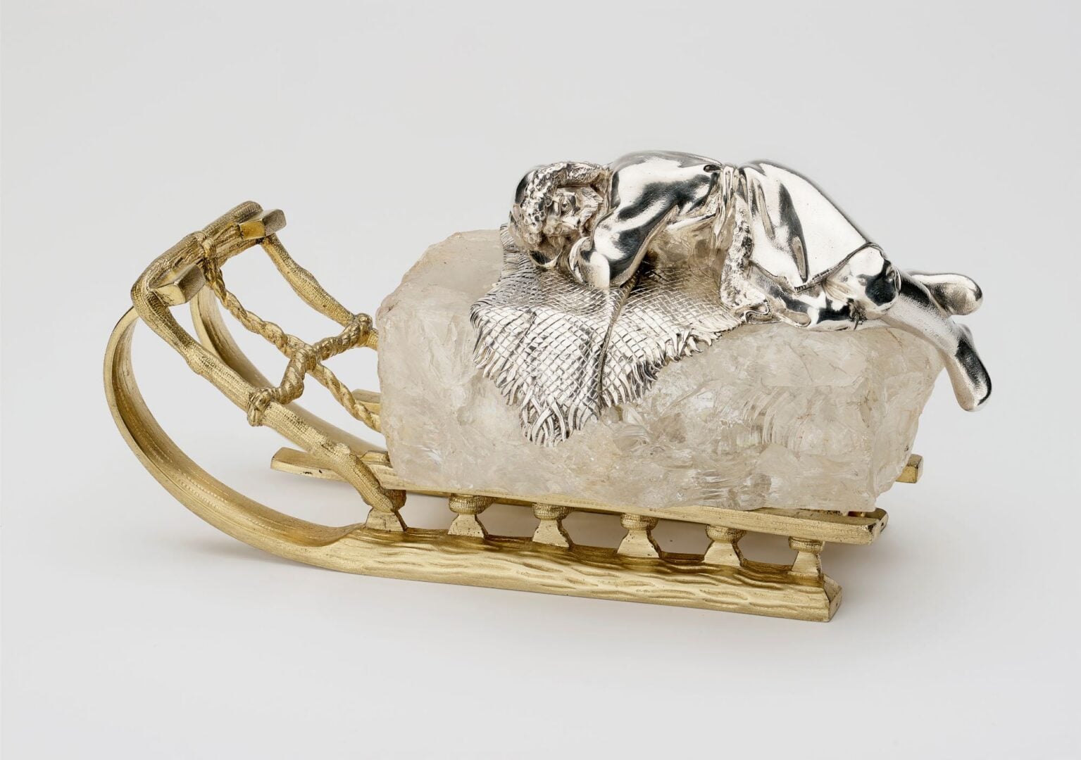 A silver and gold paperweight, in the shape of a sleigh.