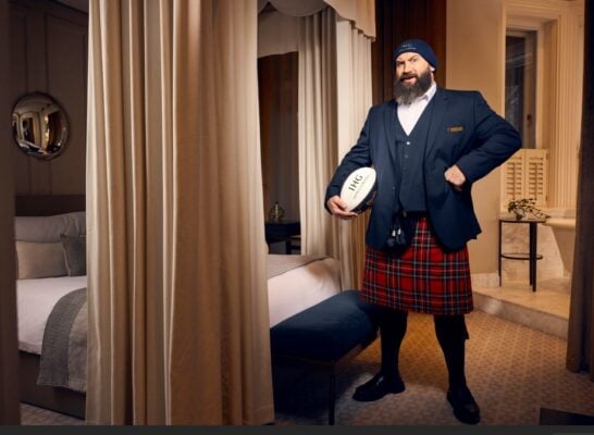 Joe Marner dressed in a kilt in a bedroom at IHG Hotels
