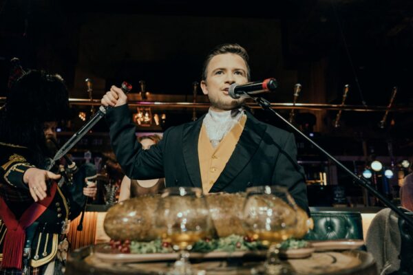 Man dressed in waistcoat and jacket standing in front of a haggis.