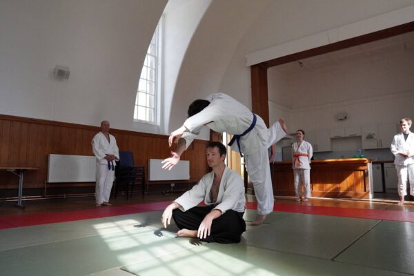 2 people participating in Jitsu with group watching on