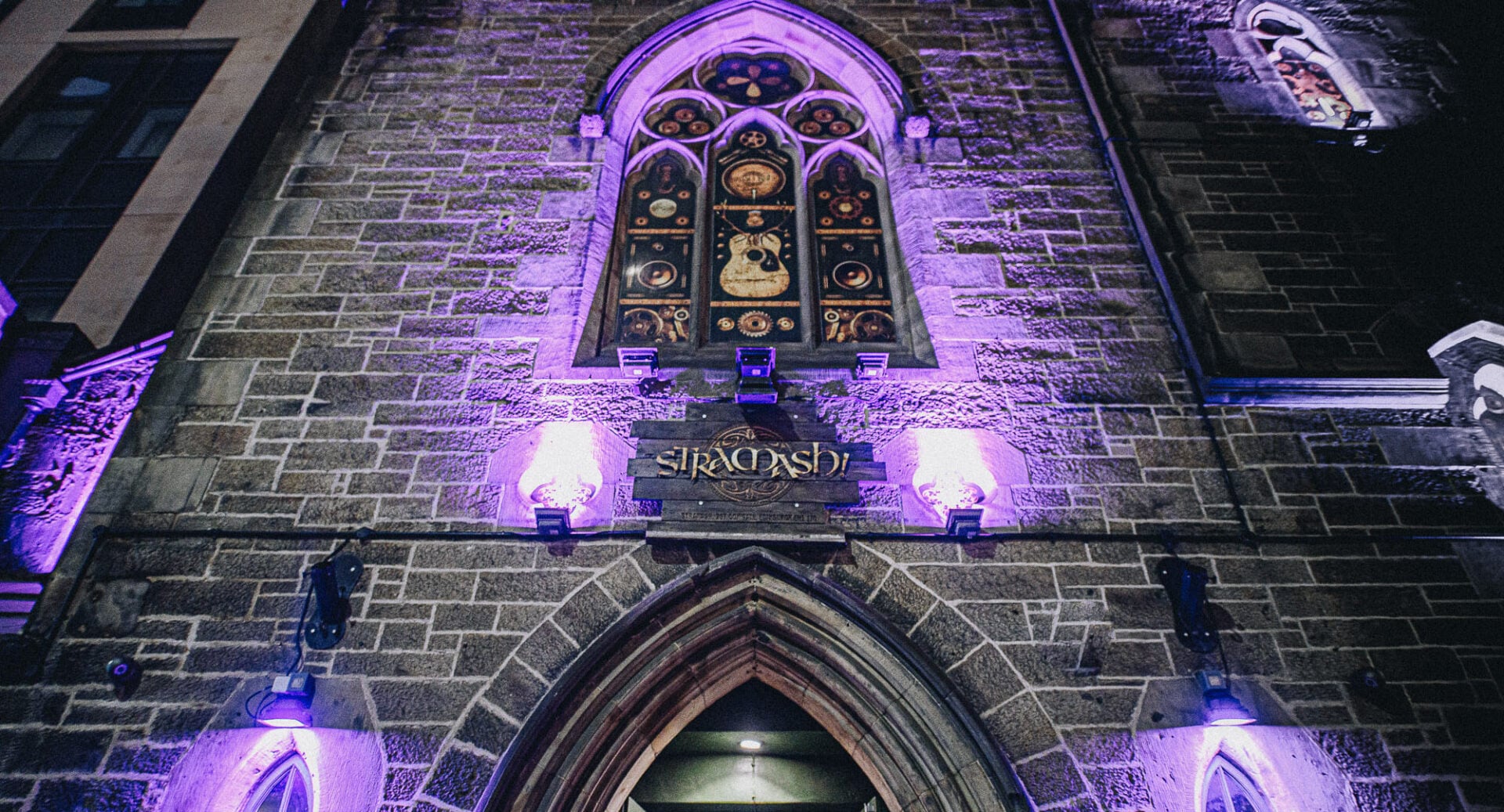 Looking up at the stained glass window of a church building.