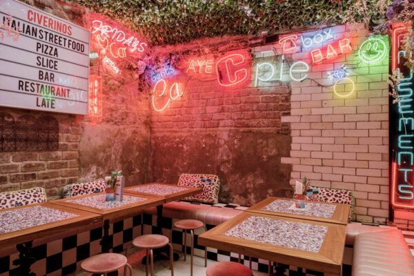 neon lights on a brick wall surrounding tabkes,© Civerinos