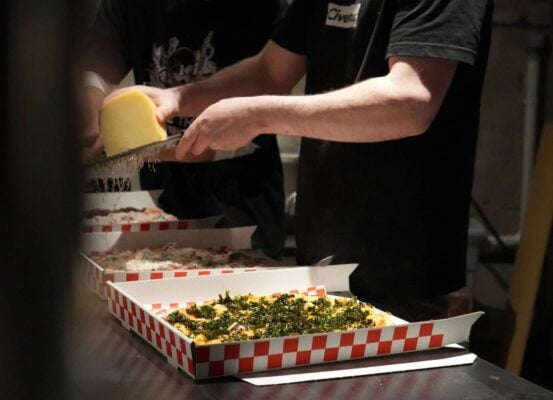 someone grating parmesan on pizza in takeaway box,© Civerinos