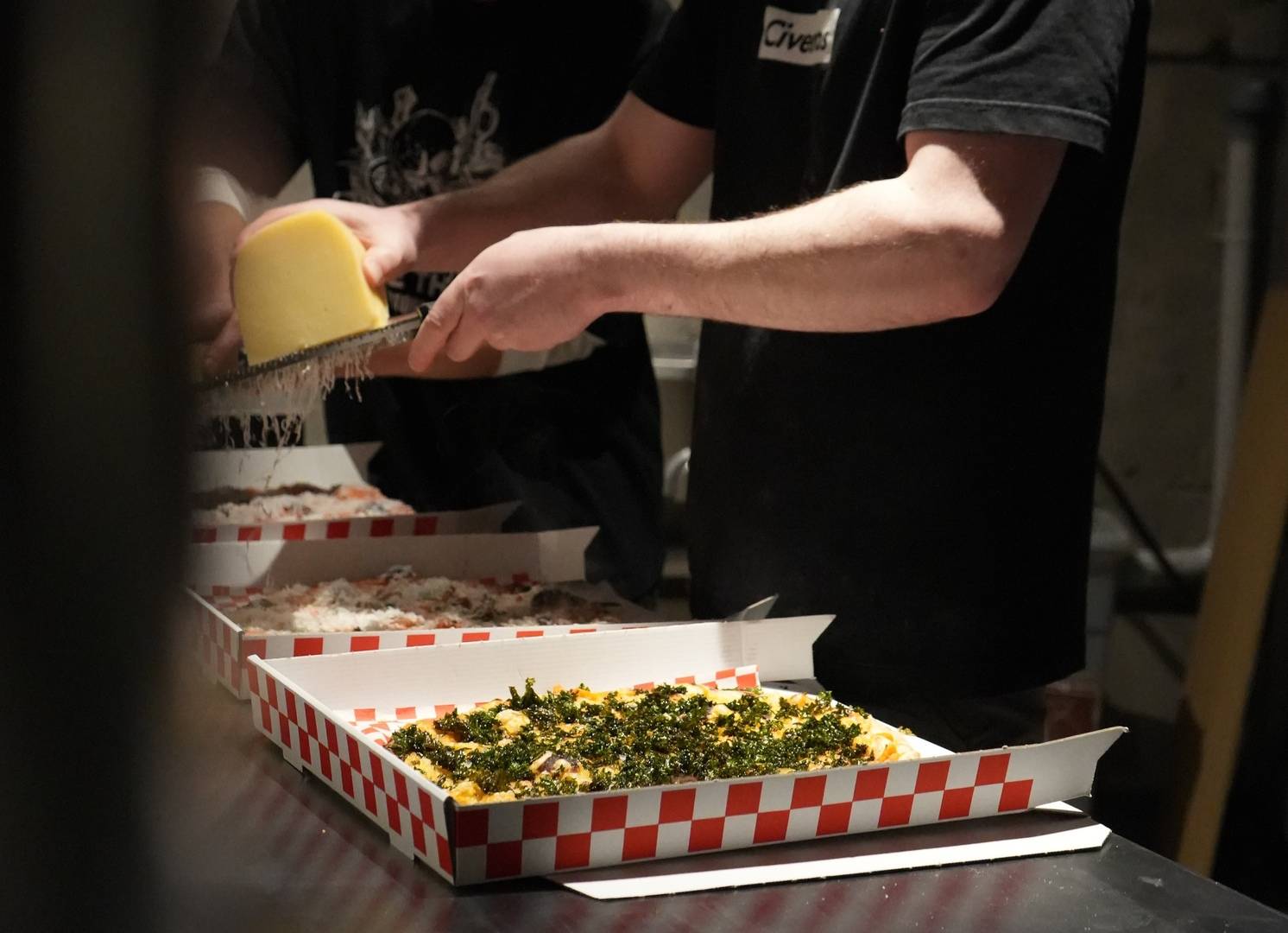 someone grating parmesan on pizza in takeaway box,© Civerinos
