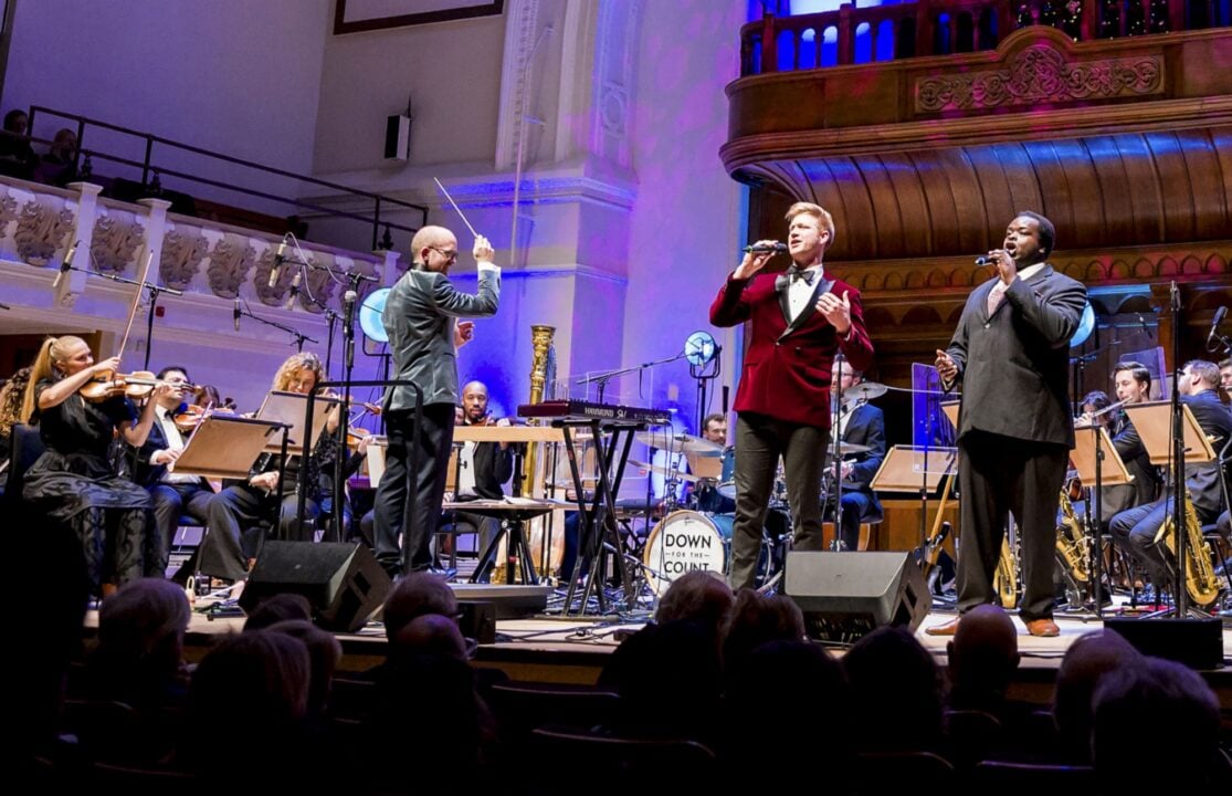 A band, with 2 singers, performing on a stage.