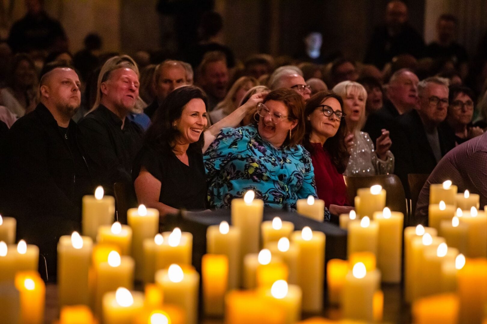 A room full of seated people, with lit candles in the foreground.