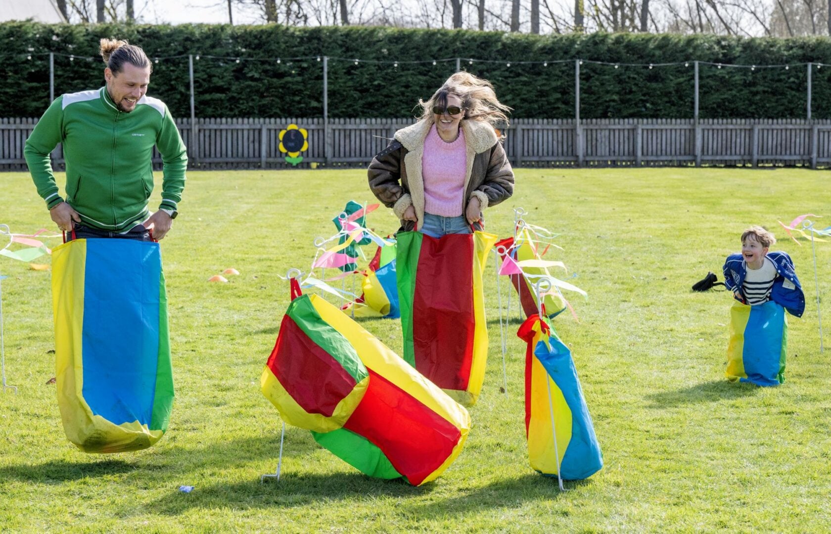 2 adults and a child doing a sack race.