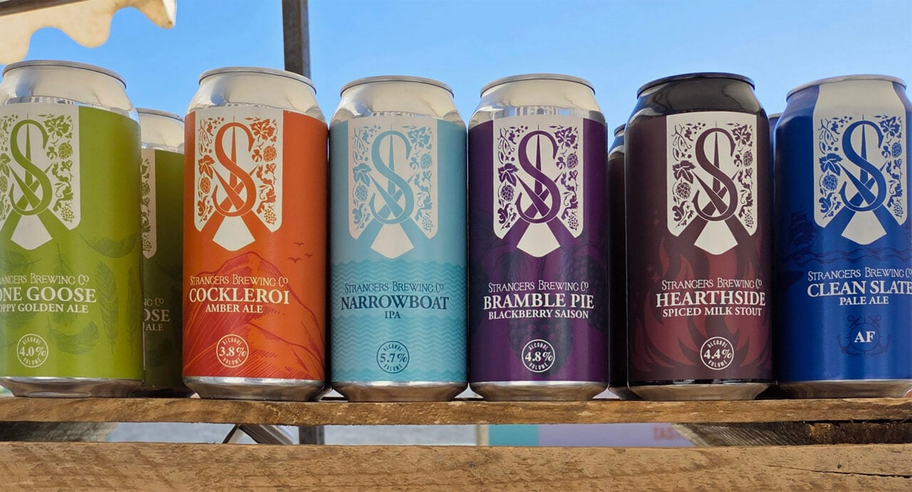 Row of beer cans on a shelf, all in different coloured labels.