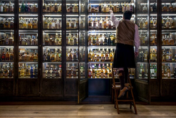 Staff member in kilt reaches into whisky cabinet at SCOTCH bar located in The Balmoral