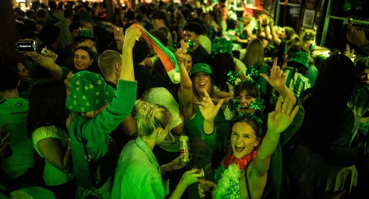 Group of people, bathed in a green light, dancing in a bar.