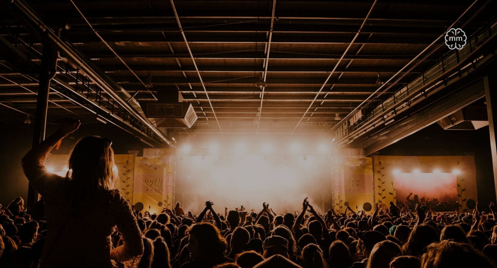 A crowded room full of people watching a performance onstage.