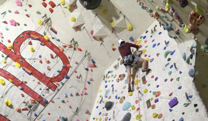 Person climbing up a climbing wall with Height Club