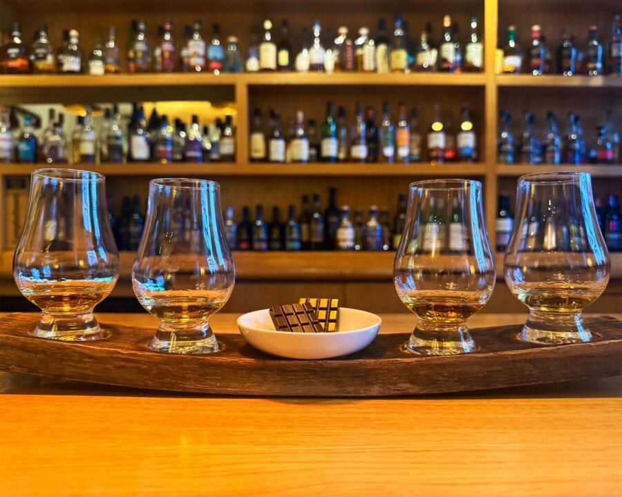 Close-up of 4 filled whisky glasses, and 2 bars of chocolate.