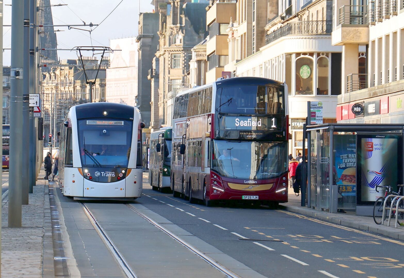 A busy street, with a bus and tram on either side of the street.