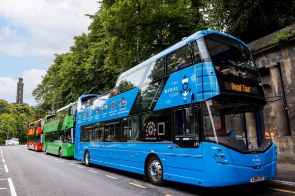 Three different Edinburgh Bus Tours buses lined up at Waterloo Place with Calton Hill in the background. Red CitySightseeing bus is at the back, green Edinburgh Tour in the middle and blue Regal tour at the front,© Edinburgh Bus Tours