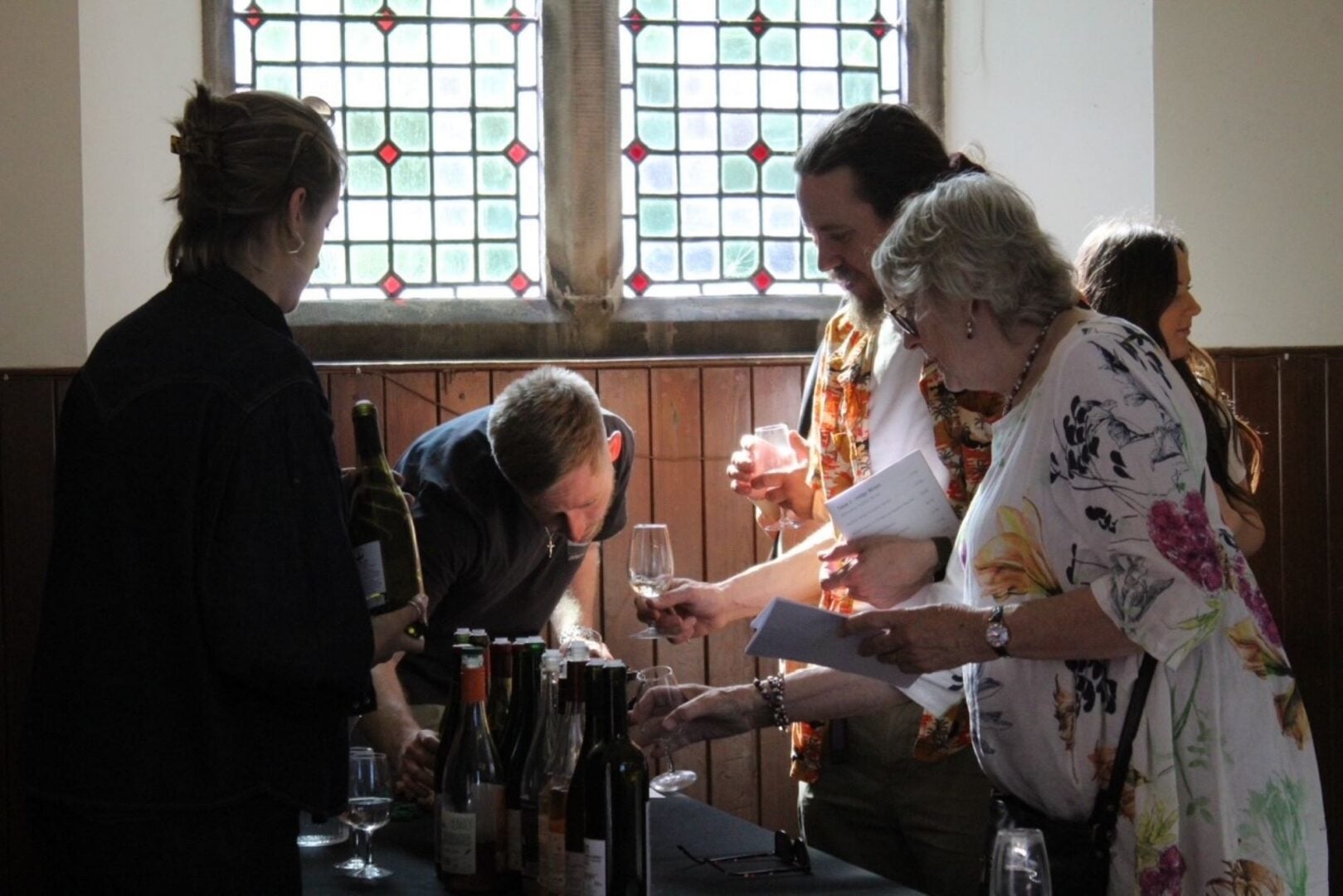 People standing around a table with wine glasses and bottles.