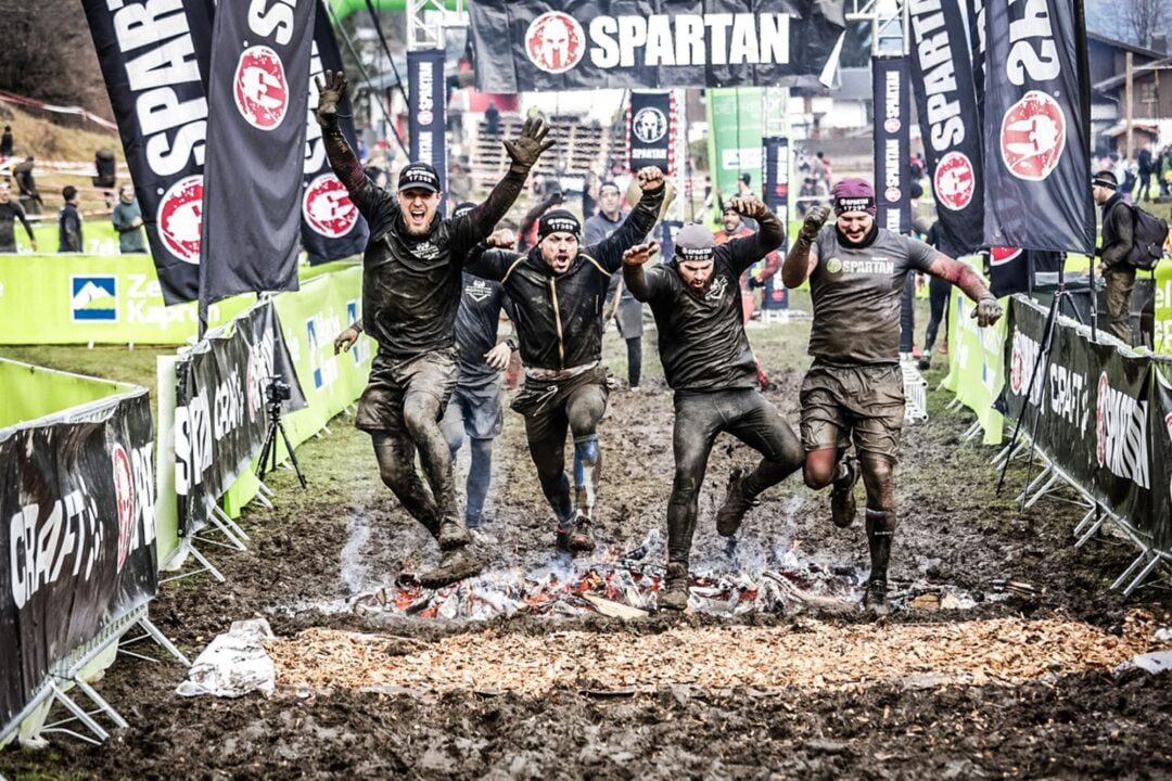Group of people running across a start/finish line.