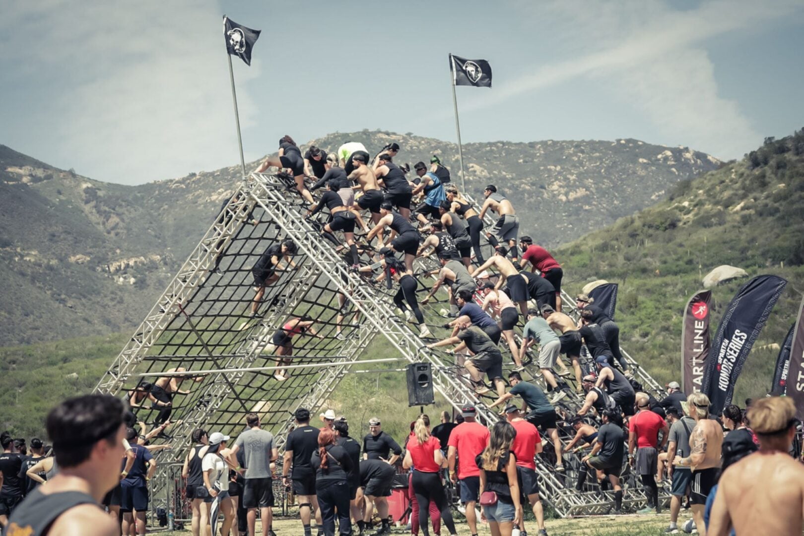 Group of people racing up a pyramid-shaped structure.