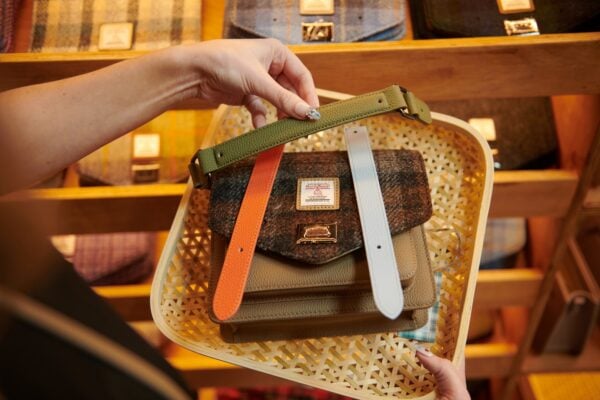 Hands choosing straps to be fitted to a handbag that has been made in a craft workshop.